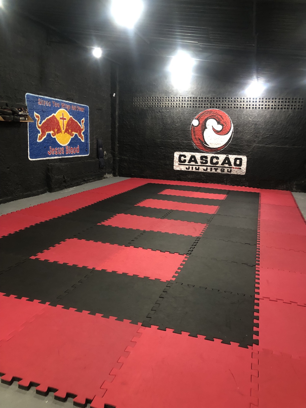 Espaço de treino com a marca Cascao Jiu Jitsu na parede